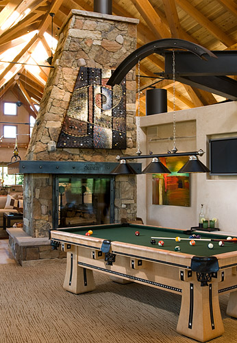 Timber frame home games room with pool table and stone fireplace